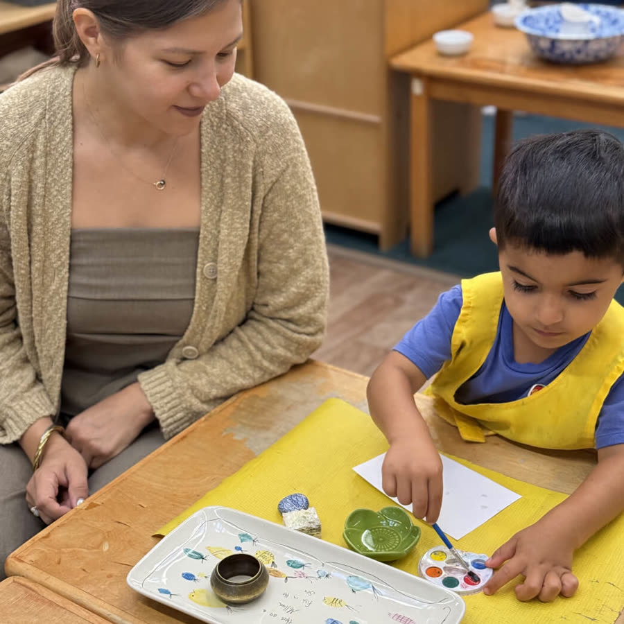 A Scripps Montessori guide working alongside a child at a classroom table