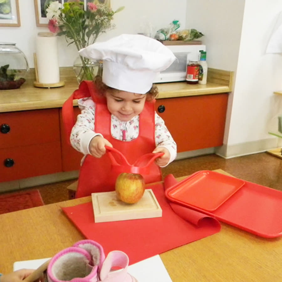 A Scripps Montessori child preparing food as part of the practical life curriculum